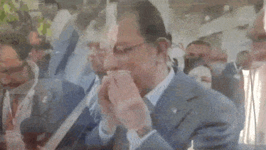 a man in a suit and tie is covering his mouth with his hands .