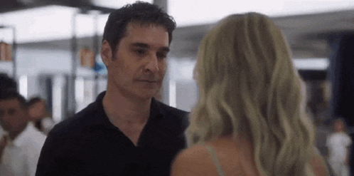 a man and a woman are standing next to each other and looking at each other in a room .