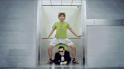 a man in a green shirt is sitting on a toilet next to a man in a suit