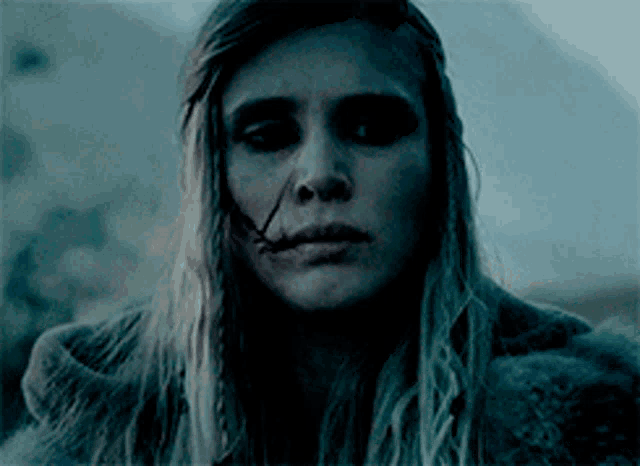 a woman with a scar on her face looks at the camera