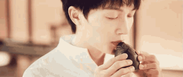 a young man in a white shirt is holding a black object in his hand .