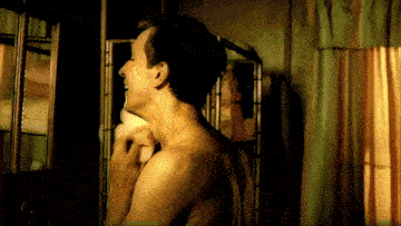 a man without a shirt is shaving his neck in front of a mirror