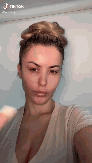 a woman without makeup is taking a selfie with a sponge in her hand .
