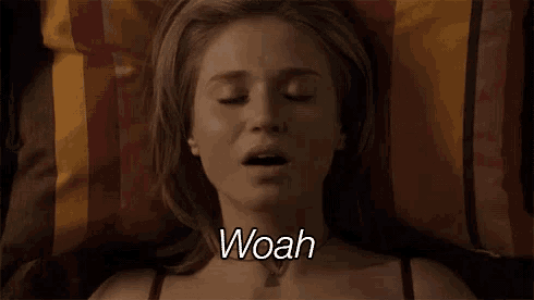 a woman is laying on a bed with her eyes closed and making a facial expression .