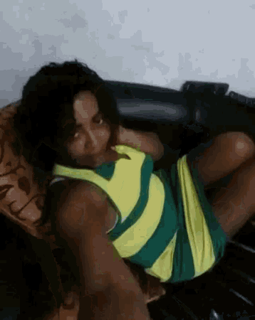 a woman in a yellow and green striped shirt is laying on a chair