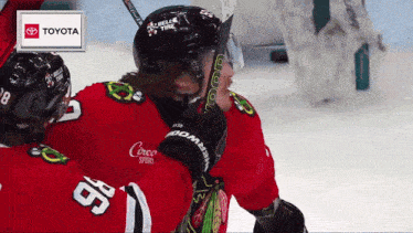 a hockey player with the number 98 on his jersey is hugging another player