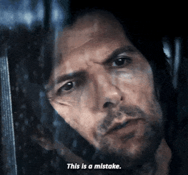 a man with a beard is looking out a window and says this is a mistake .