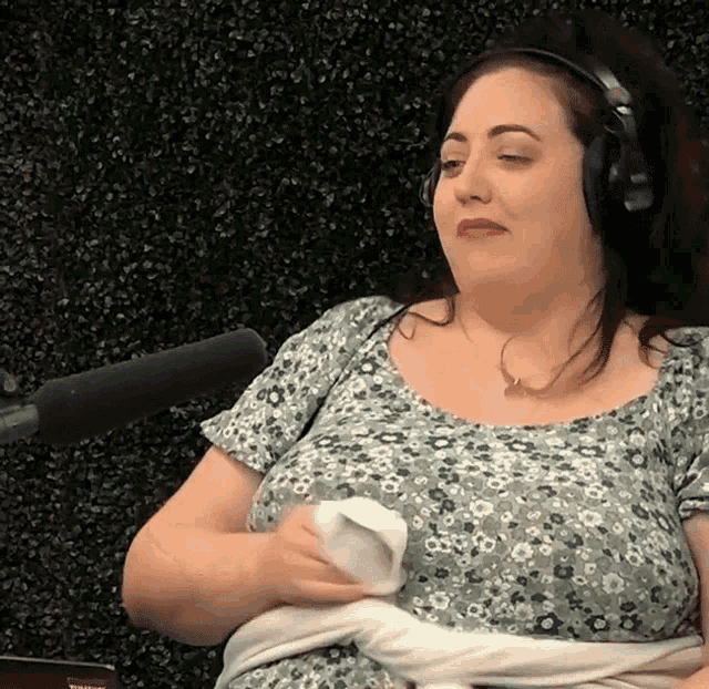 a woman wearing headphones is sitting in front of a microphone and holding a napkin