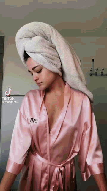 a woman wearing a pink robe and a towel wrapped around her head .