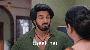 a man with a beard is talking to a woman with the words theek hai written on the bottom