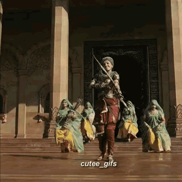 a group of women are dancing in front of a building with cutee_gifs written on the bottom right