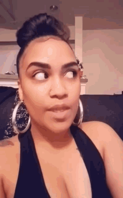 a woman wearing hoop earrings and a black tank top