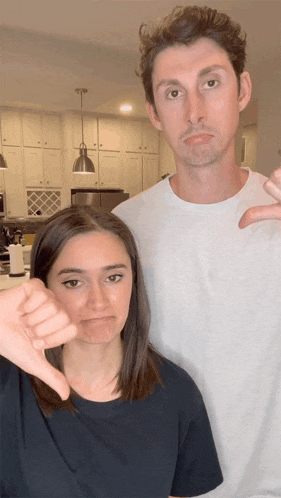 a man and a woman are giving thumbs down signs