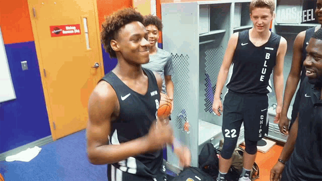 a group of basketball players are standing in a locker room and one of them has the number 22 on his shorts