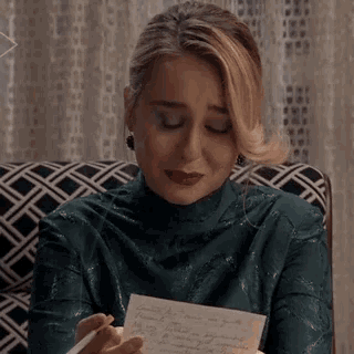 a woman is sitting on a couch writing on a piece of paper .