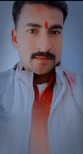 a man with a red dot on his forehead wears a white adidas jacket