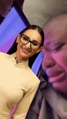 a woman wearing glasses is smiling next to a man
