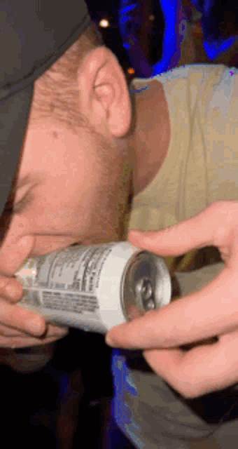 a man is drinking from a can that has a nutrition label