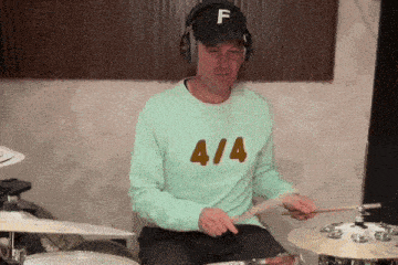 a man wearing a shirt with the number 414 on it is playing drums