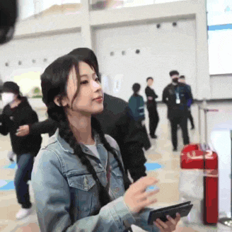 a woman in a denim jacket is holding a cell phone in her hand