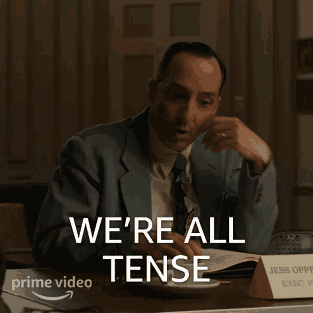 a man sitting at a desk with the words we 're all tense on the bottom