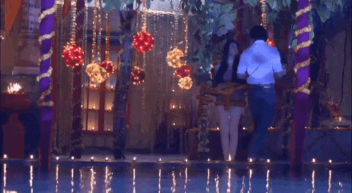 a man and a woman are standing next to each other in a room with lots of lights .