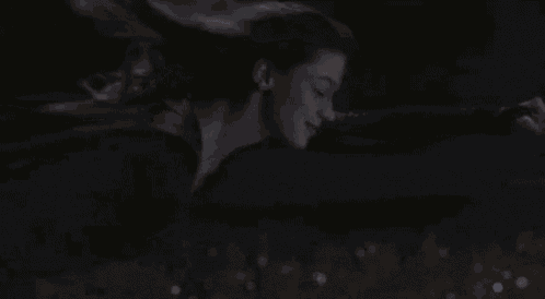 a woman in a superhero costume is flying through the air in the dark .