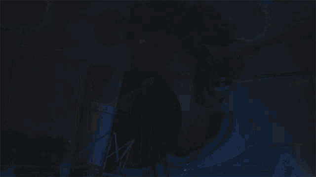 a man in a blue hoodie is standing in a dark room with blue lights on the ceiling