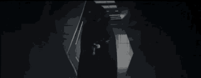 a man in a red cape is walking down a dark hallway .
