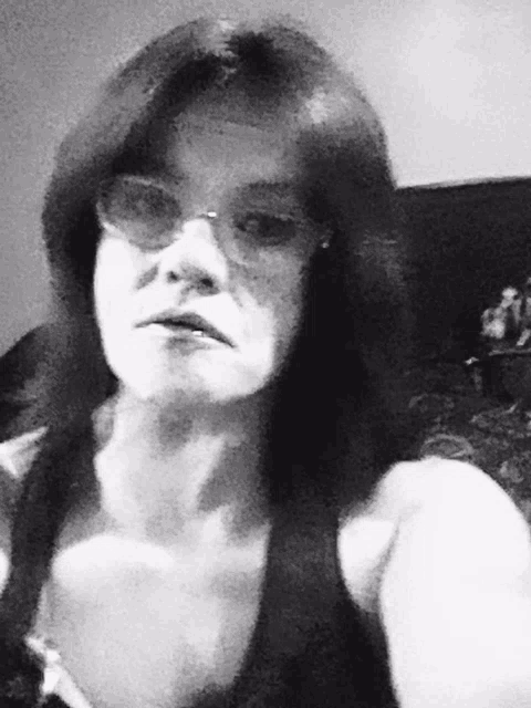 a black and white photo of a woman wearing glasses and a black tank top