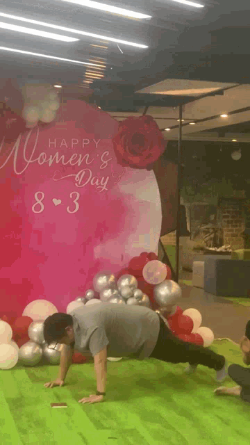 a man doing push ups in front of a sign that says happy women 's day 8 3