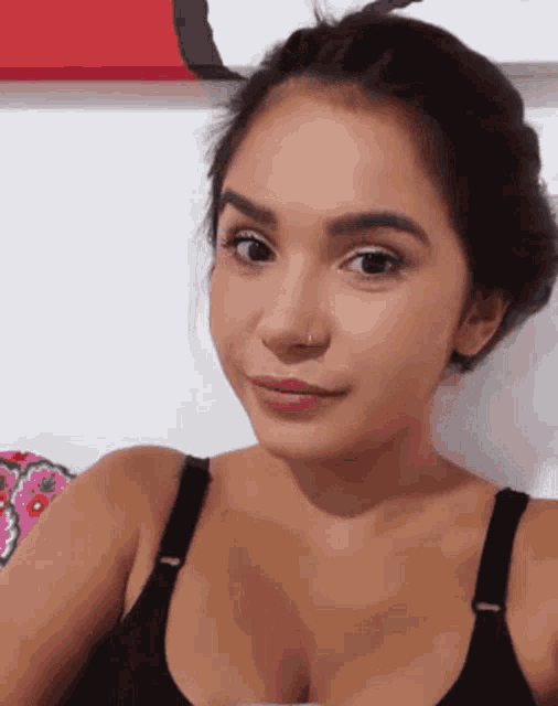 a woman wearing a black bra and a nose ring takes a selfie