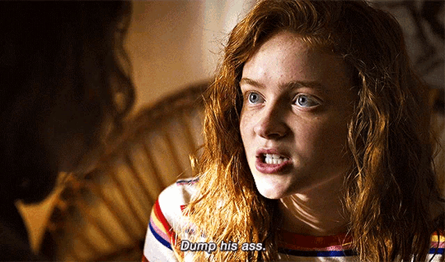 a girl with red hair is talking to another girl and says dump his ass