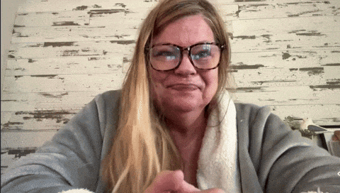 a woman wearing glasses and a sweater is smiling