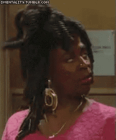a woman with dreadlocks and a pink shirt is looking down