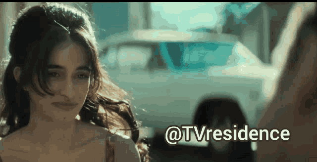 a woman in a red tank top is standing in front of a car and the words @tvresidence are below her