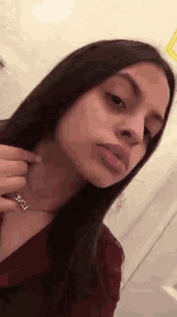 a woman is taking a selfie in a bathroom with a necklace on her neck .