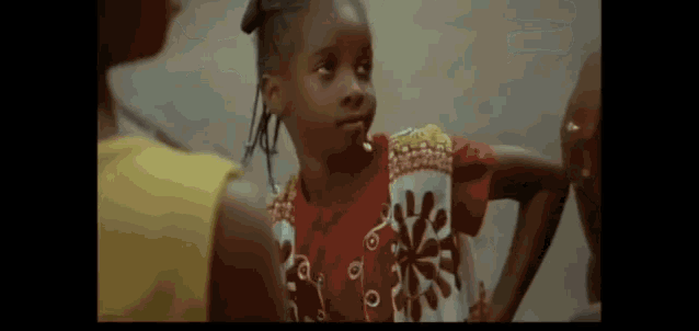 a little girl in a red shirt is standing next to another little girl in a yellow shirt .