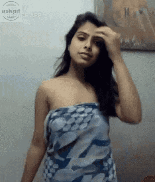 a woman wrapped in a blue towel is standing in front of a wall ..