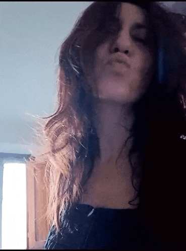 a woman with long hair making a funny face with her eyes closed