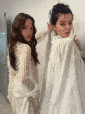 two women in white dresses are posing for a picture together