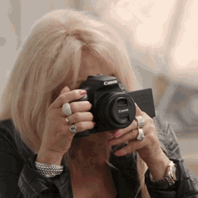 a woman is taking a picture with a canon brand camera