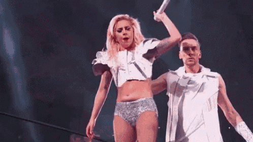 a woman in a crop top and shorts is standing next to a man in a white outfit on a stage .