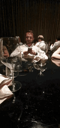 a man sits at a table with a broken wine glass that says miso