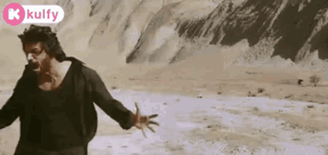a man in a black shirt is standing in the middle of a desert .