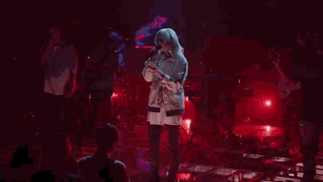 a woman singing into a microphone in front of a red background