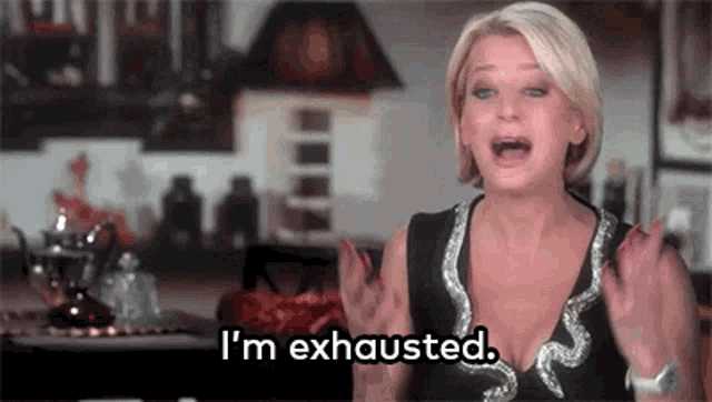 a woman is sitting at a table with her mouth open and says `` i 'm exhausted . ''
