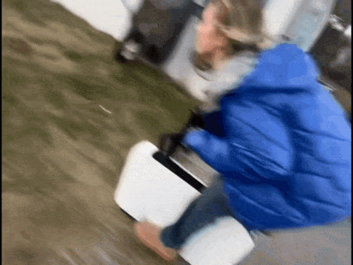 a person in a blue jacket is standing next to a white box