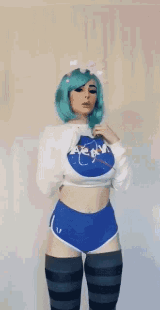 a woman with blue hair is wearing a nasa sweatshirt and shorts .