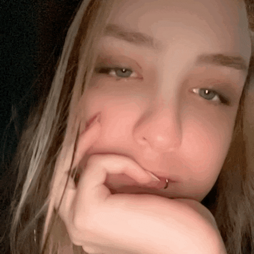 a close up of a woman with her hand on her face